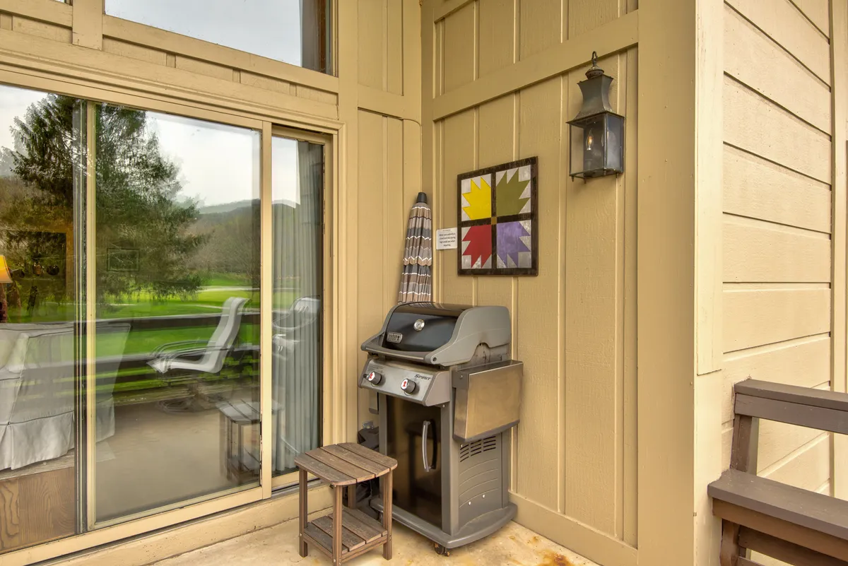 A grill takes center stage on a spacious patio, complemented by decorative wall art and outdoor seating. The setup suggests an ideal area for group barbecues, shared meals, and enjoying nature together.